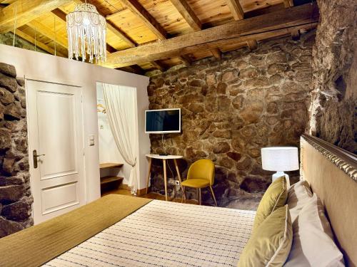 um quarto com uma cama e uma parede de pedra em Quinta do Nobre em Marialva