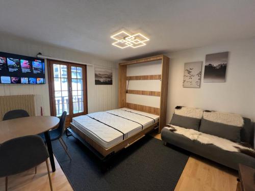 a bedroom with a bed and a couch and a table at Cosy studio for 4 near ski lift, CRETES B24 in Les Collons