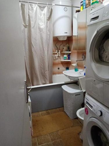 a bathroom with a toilet and a washing machine at Stan na dan in Donji Komren