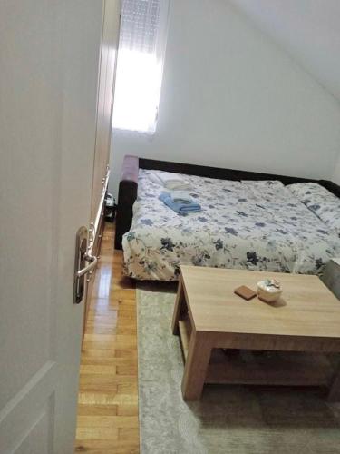 1 dormitorio con cama, mesa y puerta en Apartman Gaga, en Donji Komren