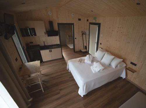 a bedroom with a white bed and a kitchen at Cabañas O Recuncho do Sor in O Barqueiro