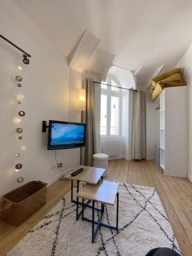 un salon avec une table et une télévision au mur dans l'établissement Cosy Mac Nab, à Vierzon