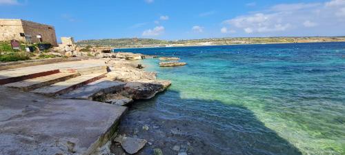 a body of water with rocks and blue water at Seaside Serenity 8 - few mins walk to the beach by QuickTrips in Mellieħa