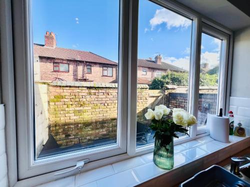 un jarrón de rosas blancas sentado en el alféizar de la ventana en The Stunning house welcomes you en Liverpool