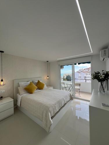 a white bedroom with a bed and a balcony at Luxury Bonanza in Benalmádena