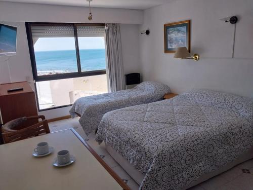 a bedroom with two beds and a table and a window at Mirador Azul Apart, 3 A,B,C in Las Grutas