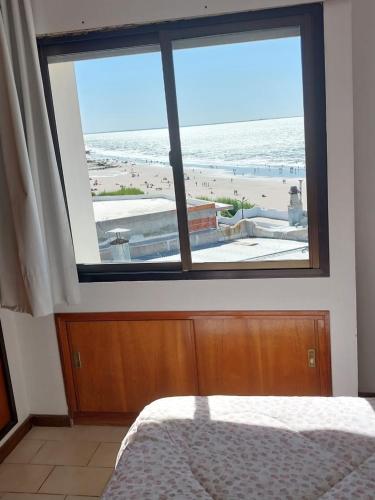 a bedroom with a view of the beach from a window at Mirador Azul Apart, 3 A,B,C in Las Grutas