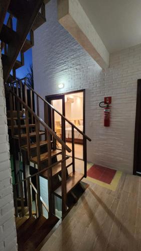 a wooden staircase in a room with a brick wall at Pousada Solarium in Canoa Quebrada