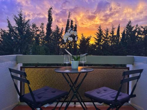 een tafel en 2 stoelen op een balkon met een zonsondergang bij Modern apartment 10 min to Vaticans Museums with parking & garden in Rome