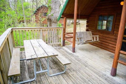 a wooden deck with a picnic table and a bench at Rustic Cabin with Views in Bloomington in Bloomington