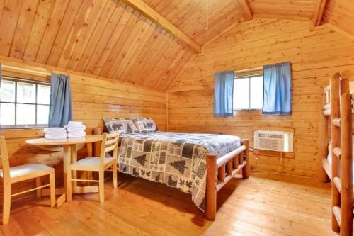a bedroom with a bed and a table in a cabin at Rustic Cabin with Pool Access in Bloomington