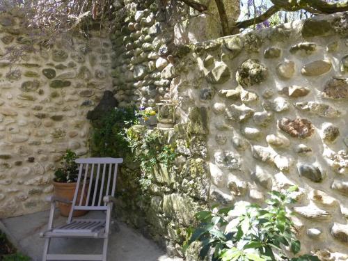 a wooden chair sitting next to a stone wall at Maison chez nous in Izeron
