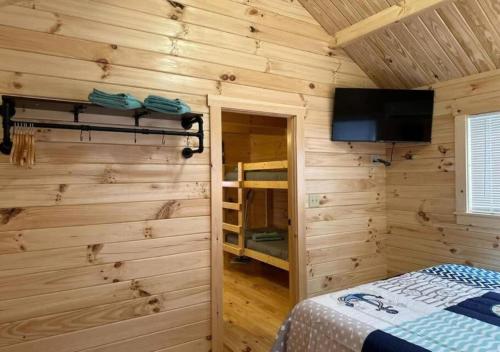 Schlafzimmer mit Holzwänden, einem TV und einem Bett in der Unterkunft Get-away Cabin in Surf City w Loft and Parking in Surf City