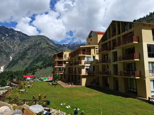 a building with a grassy field next to a mountain at The Sarai, Naran in Naran