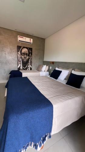 a bedroom with a large bed with a blue blanket on it at Paraíso Capitólio Suítes Pousada in Capitólio