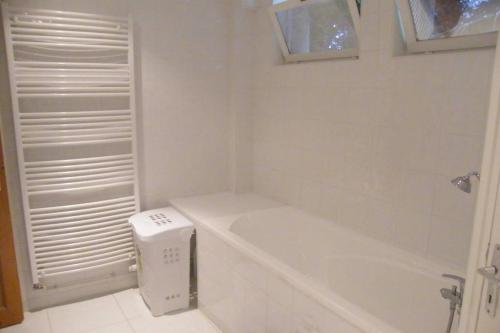 La salle de bains blanche est pourvue d'une baignoire et d'une fenêtre. dans l'établissement Proche Paris vue tour Eiffel (120m2), à Suresnes