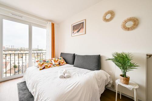 1 dormitorio con cama blanca y ventana grande en Magnifique Appart Tram Parking 4pers, en Pierrefitte-sur-Seine