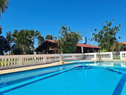 a swimming pool with a white fence around it at Chácara em Boituva com piscina e churrasqueira in Boituva