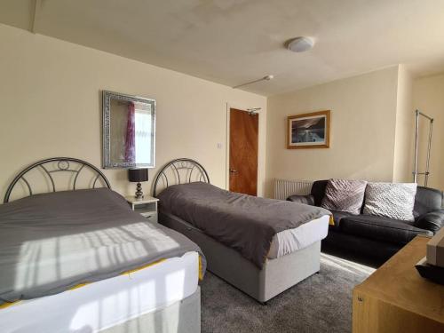 a bedroom with two beds and a couch at Ideal Apartment close to the Hustle and Bustle in Ashton under Lyne
