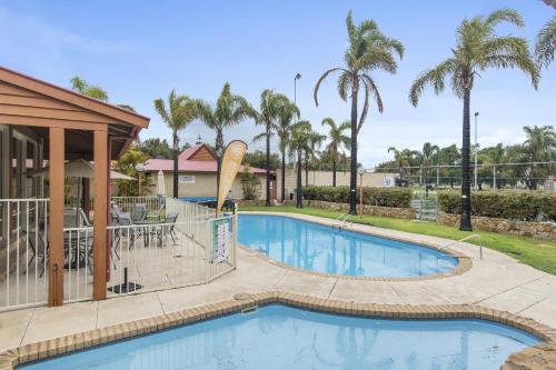 a swimming pool at a resort with palm trees at Discovery Parks - Bunbury Foreshore in Bunbury