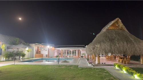 un complejo con piscina y sombrilla de paja en CABAÑA DE LUJO EN SABANGRANDE, en Sabanagrande