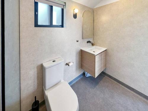 a bathroom with a white toilet and a sink at BeachComber holiday house in Marengo