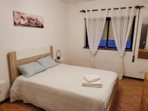 a bedroom with a bed with white sheets and a window at Chill House in Figueira da Foz