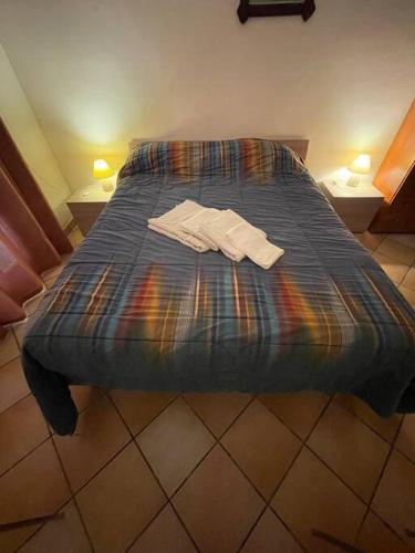 Una cama con un edredón azul con dos camisas. en Appartamento a Leuca, en Marina di Leuca