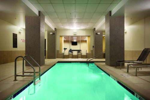 - une piscine avec 2 chaises dans un bâtiment dans l'établissement Hyatt Place Des Moines Downtown, à Des Moines