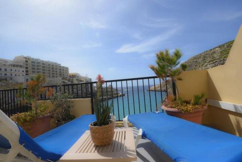 a balcony with blue chairs and a view of the ocean at Seafront duplex Penthouse with Terrace overlooking Xlendi Bay in Xlendi