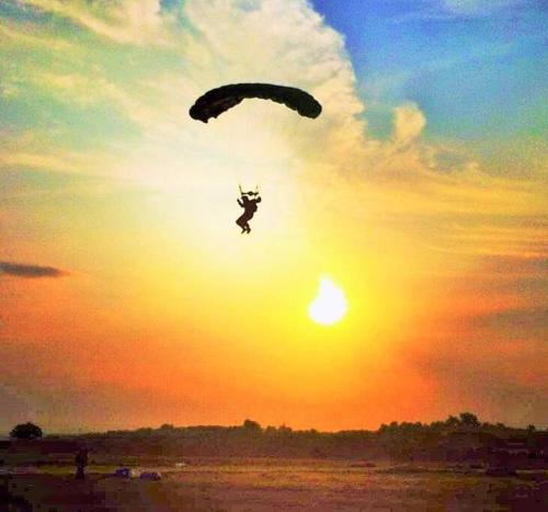 a person is flying in the sky with a parachute at Chácara em Boituva com piscina e churrasqueira in Boituva