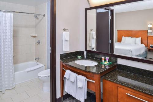 a bathroom with a sink and a toilet and a bed at Hyatt Place Herndon Dulles Airport - East in Herndon