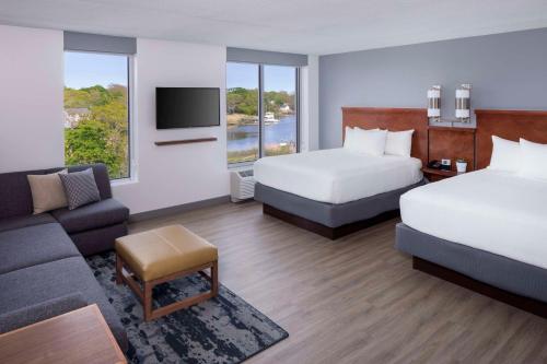 a hotel room with two beds and a couch at Hyatt Place Long Island East End in Riverhead