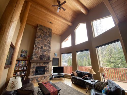 a living room with a large vaulted ceiling with large windows at Morrisey Chalet at Sun Peaks in Sun Peaks
