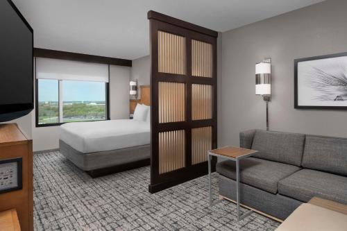 a living room with a couch and a bed and a room with a television at Hyatt Place Sugar Land in Sugar Land