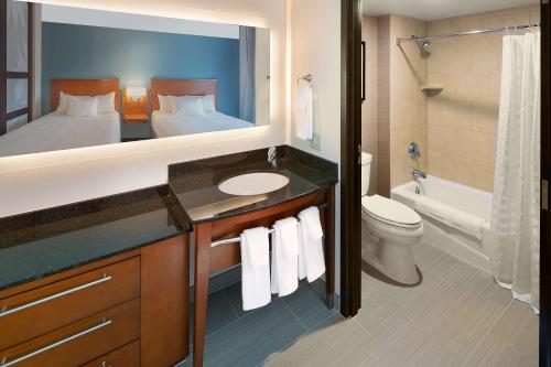 a bathroom with a sink and a bed and a mirror at Hyatt Place Madison/Downtown in Madison
