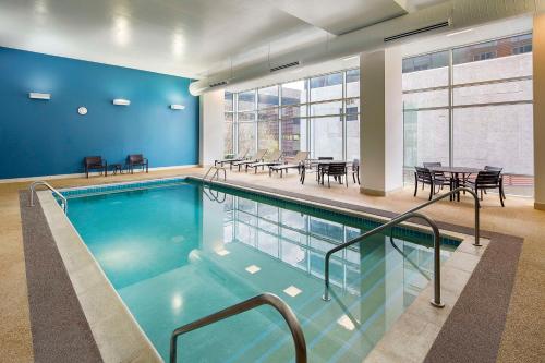 a swimming pool in a building with tables and chairs at Hyatt Place Madison/Downtown in Madison