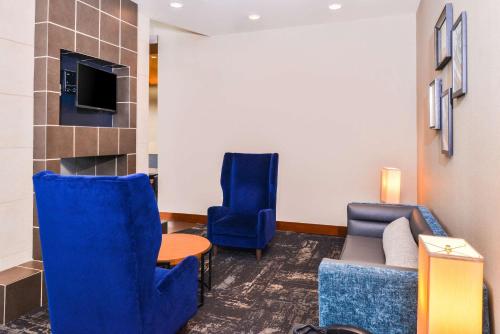 a waiting room with blue chairs and a couch and a tv at Hyatt Place Chesapeake in Chesapeake