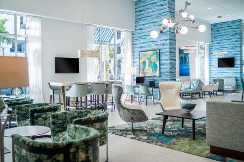 a lobby with chairs and tables and a dining room at Hyatt Place West Palm Beach in West Palm Beach