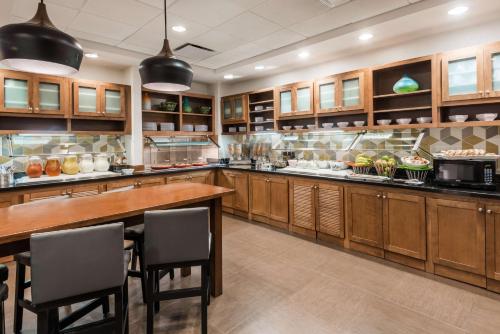 a large kitchen with wooden cabinets and a table and chairs at Hyatt Place Bentonville Rogers in Rogers