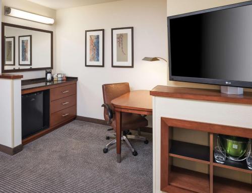 a hotel room with a desk with a tv and a table at Hyatt Place South Bend/Mishawaka in South Bend