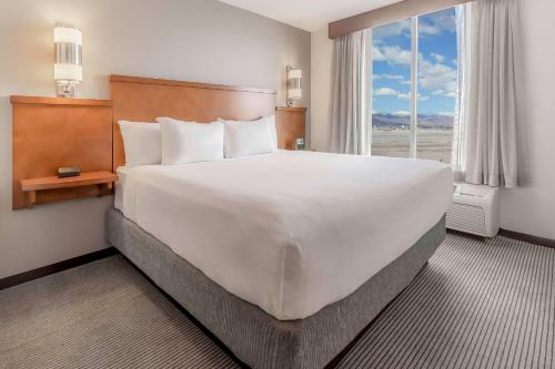 a large white bed in a hotel room with a window at Hyatt Place Salt Lake City Airport in Salt Lake City