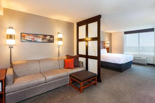een hotelkamer met een bank en een bed bij Hyatt Place Sacramento Roseville in Roseville