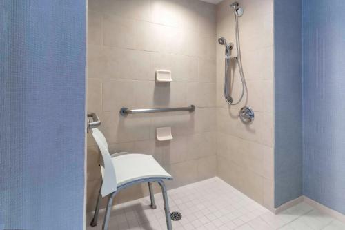 a shower with a white chair in a bathroom at Hyatt Place Salt Lake City Airport in Salt Lake City