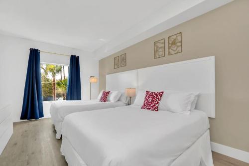 two white beds in a room with blue curtains at Casa Magical 1mile to Disney in Orlando