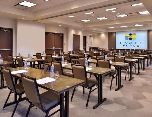 a conference room with tables and chairs and a screen at Hyatt Place Garden City in Garden City