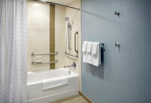 a bathroom with a tub and a shower with towels at Hyatt Place Cleveland/Lyndhurst/Legacy Village in Lyndhurst