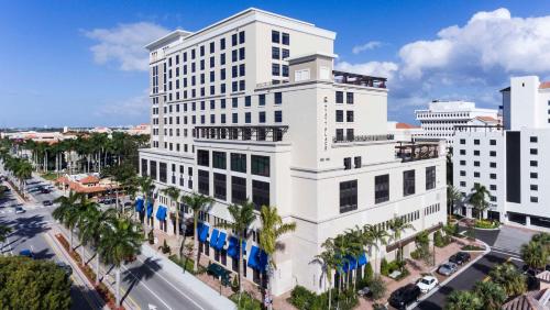 a tall white building with palm trees in front of a street at Hyatt Place Boca Raton in Boca Raton