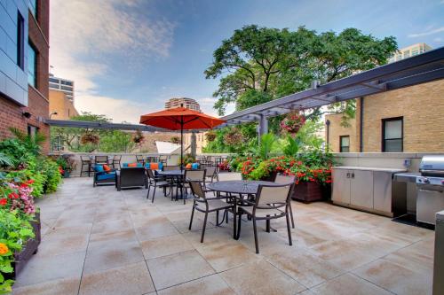 an outdoor patio with tables and chairs and an umbrella at Hyatt House Chicago/Evanston in Evanston