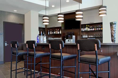 a bar with four stools in a room at Hyatt Place Houston NW Vintage Park in Houston